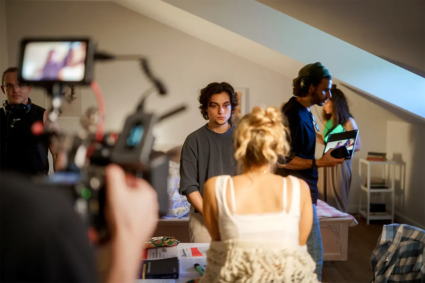 Dreh in einem Dachzimmer-Set, Team filmt eine Szene mit Kamera und Monitor, Standbild aus dem IAF Abschlussfilm Unfruchtbar
