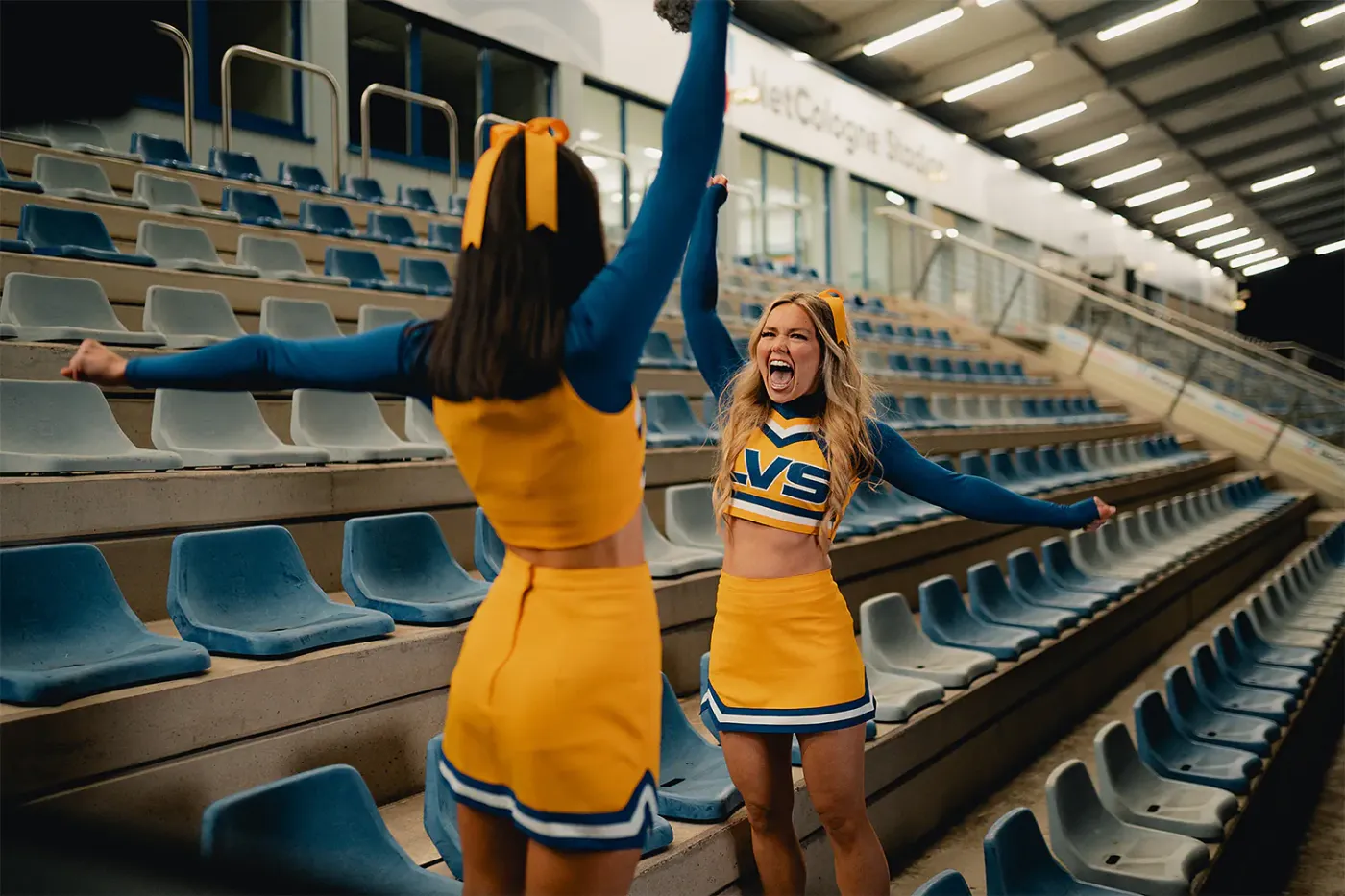 Zwei Cheerleaderinnen jubeln ausgelassen auf einer Stadiontreppe, Standbild aus dem IAF Abschlussfilm Cheerleader